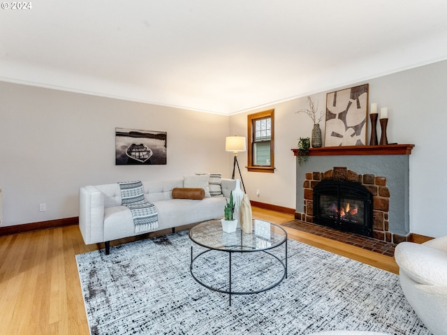 living room with a stone fireplace, ornamental molding, and hardwood / wood-style flooring