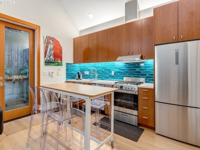 kitchen with decorative backsplash, stainless steel appliances, vaulted ceiling, sink, and light hardwood / wood-style flooring