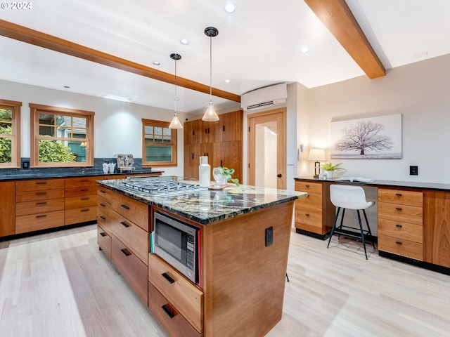 kitchen featuring stainless steel appliances, a kitchen breakfast bar, a wall unit AC, decorative light fixtures, and a kitchen island