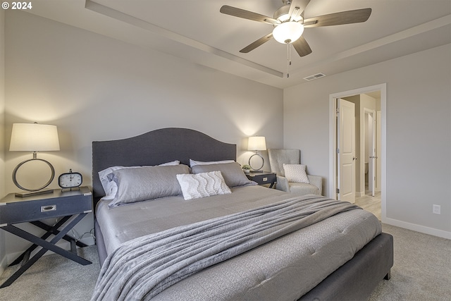 bedroom featuring light carpet, a raised ceiling, and ceiling fan