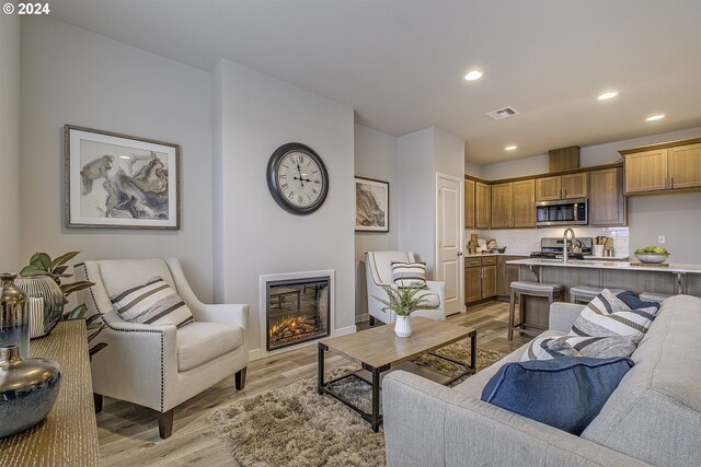 living room featuring sink and light hardwood / wood-style flooring