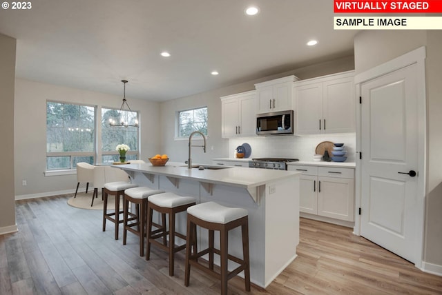 kitchen featuring white cabinets, a center island with sink, stainless steel appliances, and sink