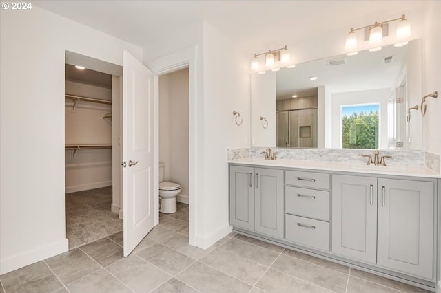 bathroom with tile patterned flooring, vanity, toilet, and walk in shower