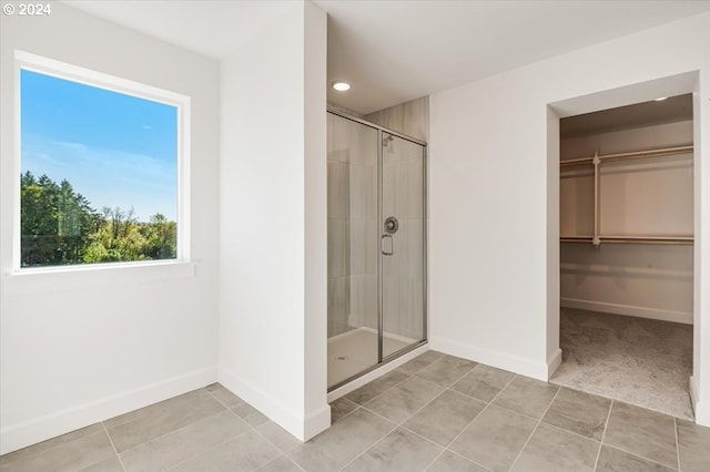 bathroom with tile patterned floors, a wealth of natural light, and a shower with shower door