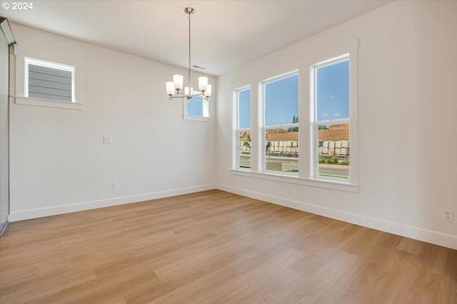 spare room featuring light wood-type flooring and an inviting chandelier