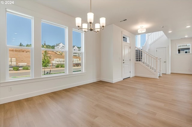 unfurnished dining area featuring light hardwood / wood-style flooring and a notable chandelier