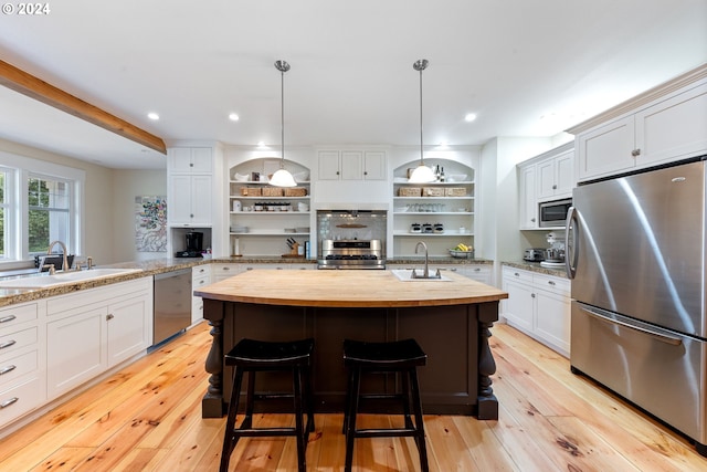 kitchen with appliances with stainless steel finishes, butcher block counters, and white cabinets