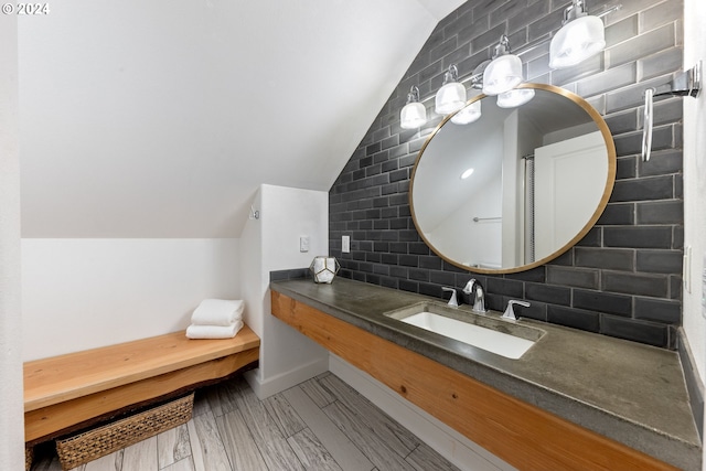 bathroom with vaulted ceiling, wood-type flooring, vanity, and decorative backsplash