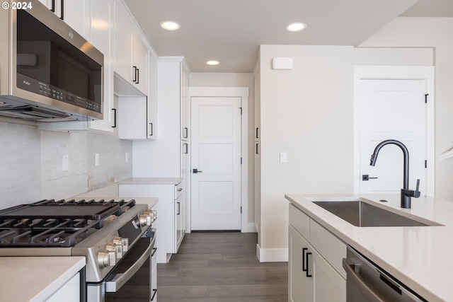 kitchen with dark wood-type flooring, sink, tasteful backsplash, white cabinetry, and appliances with stainless steel finishes