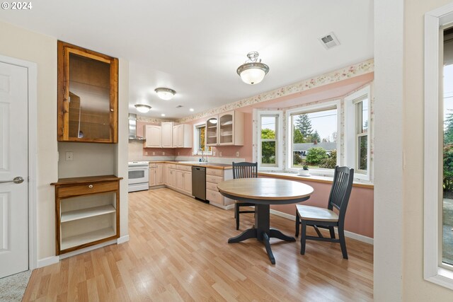 kitchen featuring sink, wall chimney exhaust hood, stainless steel dishwasher, light wood-type flooring, and electric stove