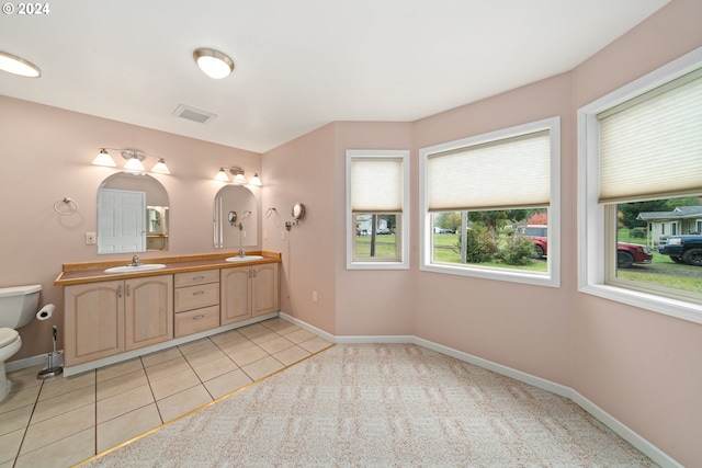 bathroom with toilet, vanity, and tile patterned flooring