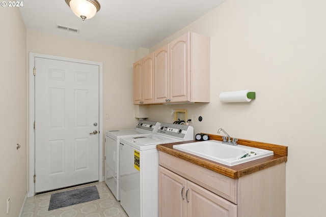 washroom featuring cabinets, sink, and washer and dryer