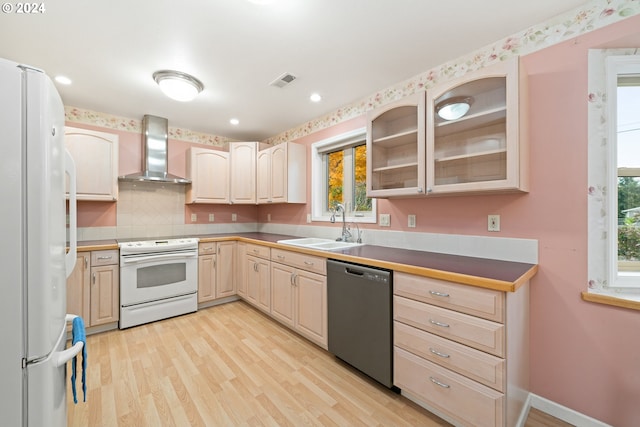 kitchen featuring white appliances, wall chimney range hood, a healthy amount of sunlight, and sink