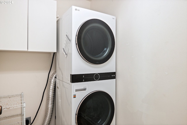 clothes washing area with cabinets and stacked washer and dryer