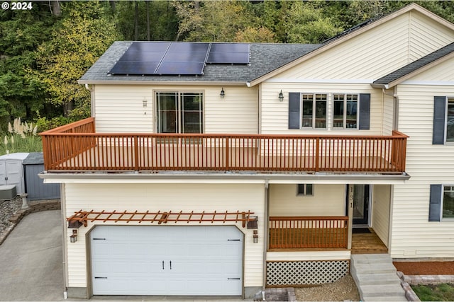 rear view of property featuring solar panels and a garage