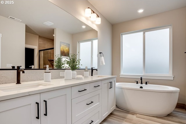 3818 S 44th Ln, Ridgefield, WA 98642 - bathroom with double vanity, wood finished floors, a shower stall, a freestanding bath, and plenty of natural light