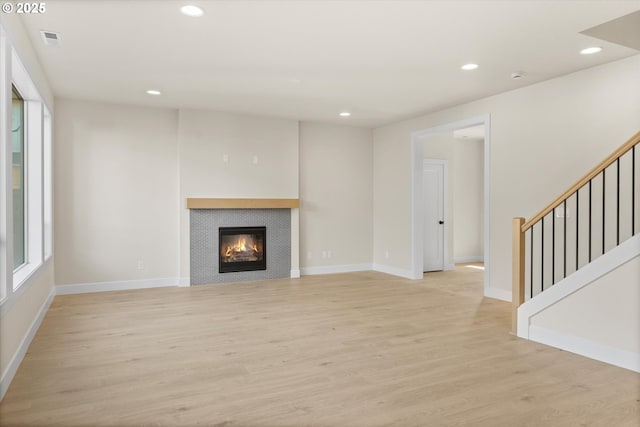 unfurnished living room with light hardwood / wood-style floors and a tile fireplace