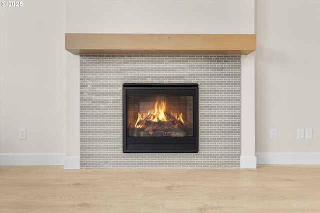 details featuring a tiled fireplace and hardwood / wood-style floors