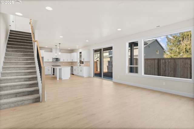 unfurnished living room featuring sink and light hardwood / wood-style flooring