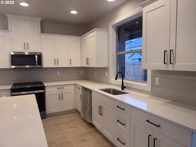 kitchen featuring appliances with stainless steel finishes, white cabinetry, and sink