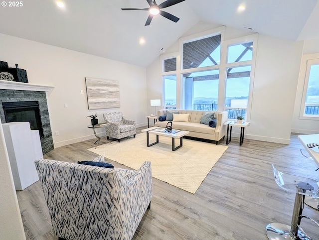 living room featuring a fireplace, high vaulted ceiling, ceiling fan, and wood finished floors