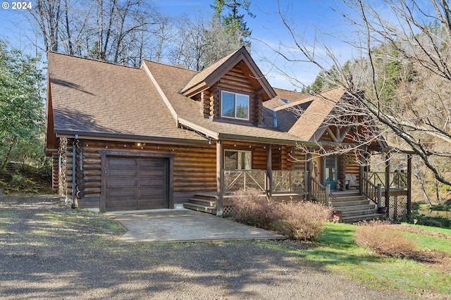 log-style house featuring covered porch and a garage