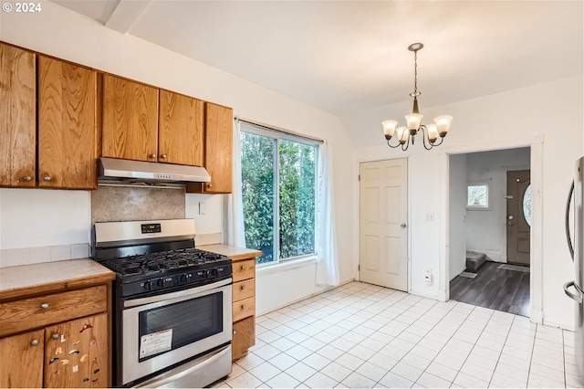 kitchen with tasteful backsplash, hanging light fixtures, light hardwood / wood-style flooring, an inviting chandelier, and stainless steel range with gas stovetop