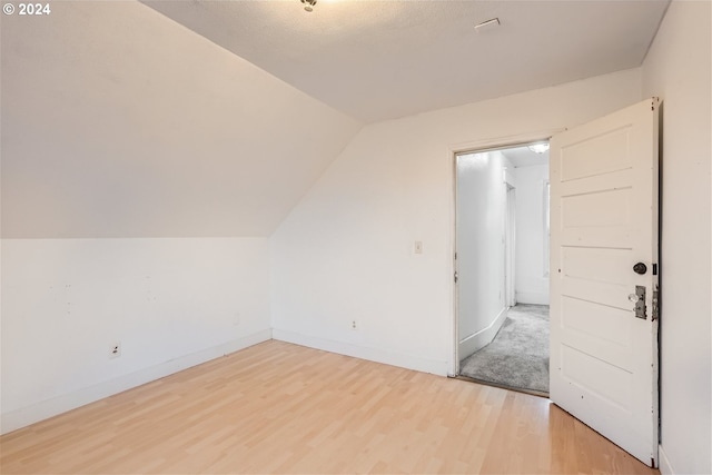 additional living space featuring lofted ceiling and light wood-type flooring