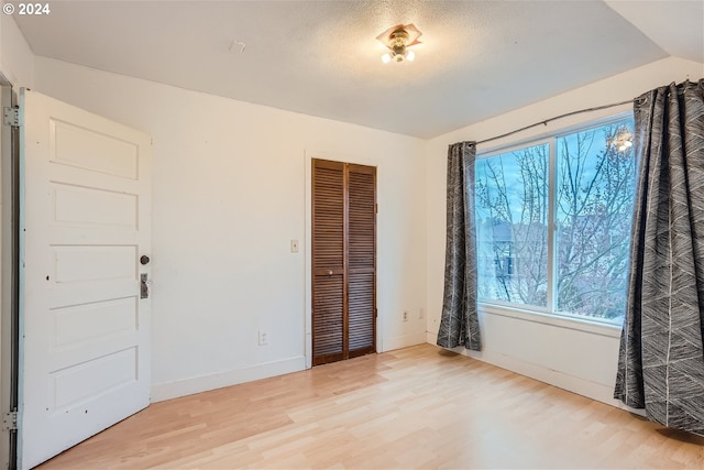 unfurnished bedroom featuring a closet, multiple windows, and light wood-type flooring