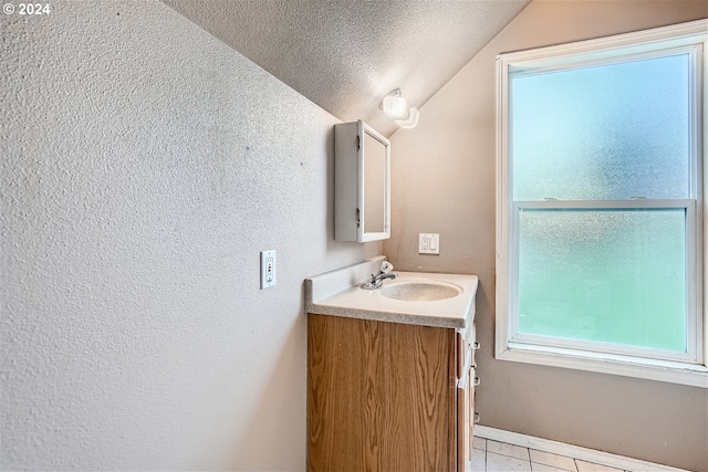 bathroom with lofted ceiling, a textured ceiling, tile flooring, and vanity with extensive cabinet space