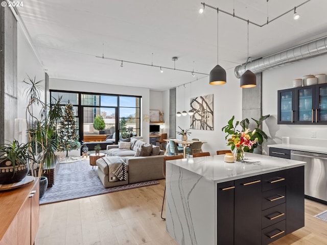 kitchen with decorative light fixtures, light hardwood / wood-style flooring, a kitchen island, and stainless steel dishwasher