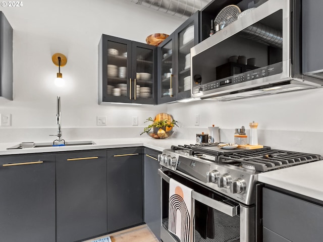 kitchen with hanging light fixtures, light hardwood / wood-style flooring, stainless steel appliances, and sink