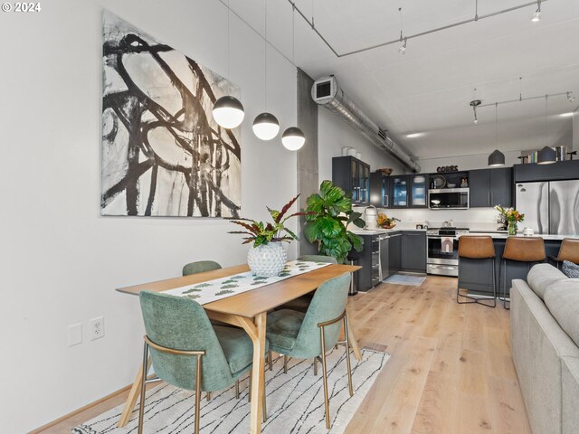 kitchen featuring stainless steel appliances, a sink, light wood-style flooring, a kitchen bar, and light countertops