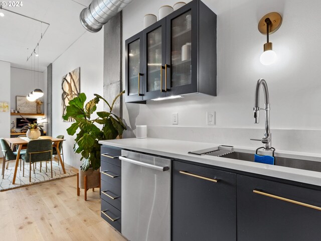 kitchen featuring appliances with stainless steel finishes, light wood-type flooring, light countertops, and a sink