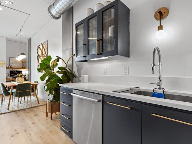 420 NW 11th Ave Unit 502, Portland, OR 97209 - kitchen with stainless steel dishwasher, a sink, light countertops, light wood-style flooring, and hanging light fixtures