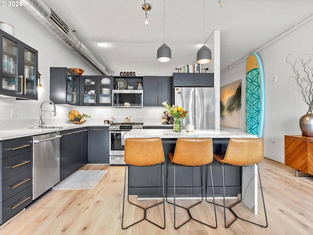 kitchen featuring sink, pendant lighting, light wood-type flooring, and appliances with stainless steel finishes