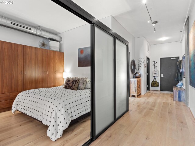 bedroom with light hardwood / wood-style floors and a closet