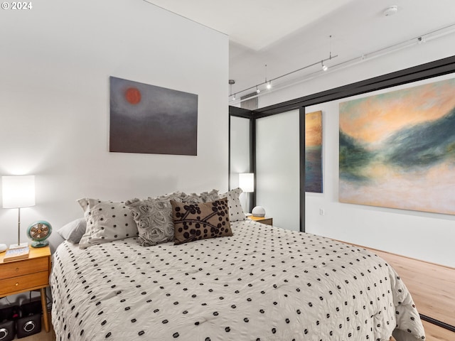 bedroom with wood-type flooring and track lighting