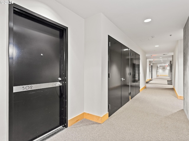hallway featuring carpet floors, baseboards, and recessed lighting