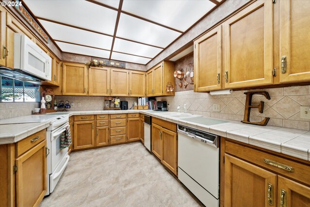 kitchen with tile countertops, white appliances, decorative backsplash, and sink