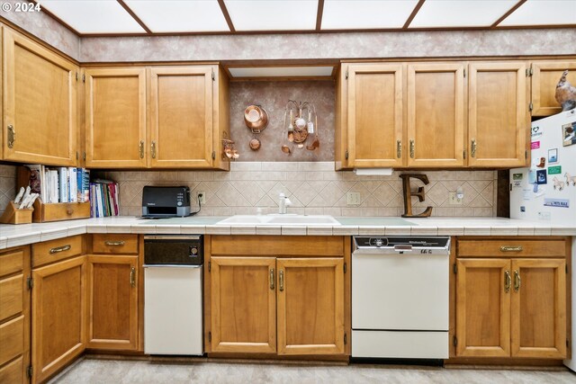 kitchen with white appliances, backsplash, sink, and tile counters