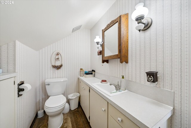 bathroom featuring hardwood / wood-style floors, vaulted ceiling, toilet, and vanity