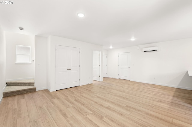 interior space with light wood-type flooring and an AC wall unit