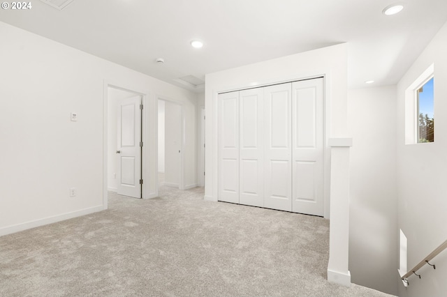 unfurnished bedroom with light carpet and a closet