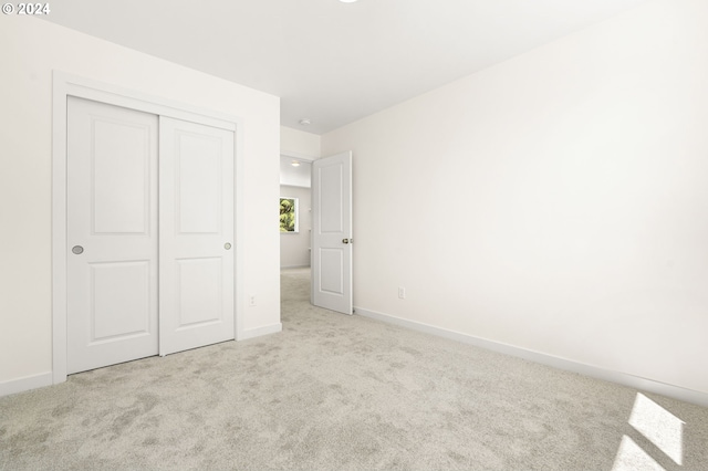 unfurnished bedroom featuring light carpet and a closet