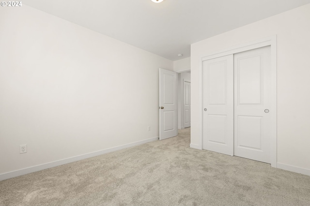 unfurnished bedroom with light carpet and a closet