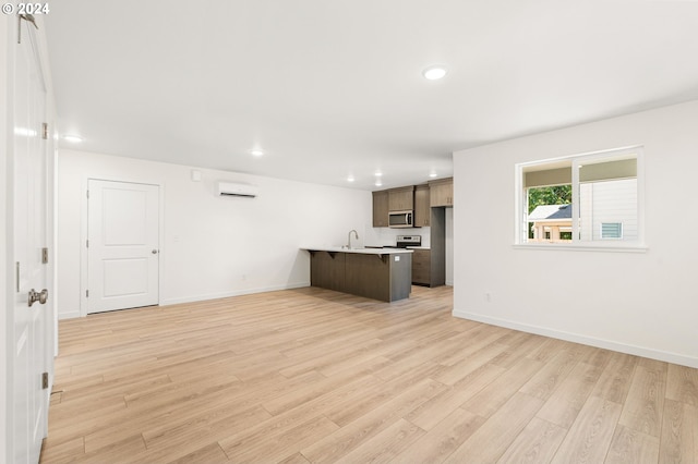 unfurnished living room featuring light wood-type flooring, sink, and a wall unit AC