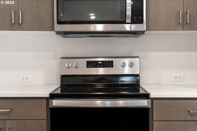 kitchen featuring backsplash, dark brown cabinetry, light stone countertops, and appliances with stainless steel finishes