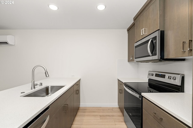 kitchen featuring sink, stainless steel appliances, a wall mounted air conditioner, and light hardwood / wood-style flooring