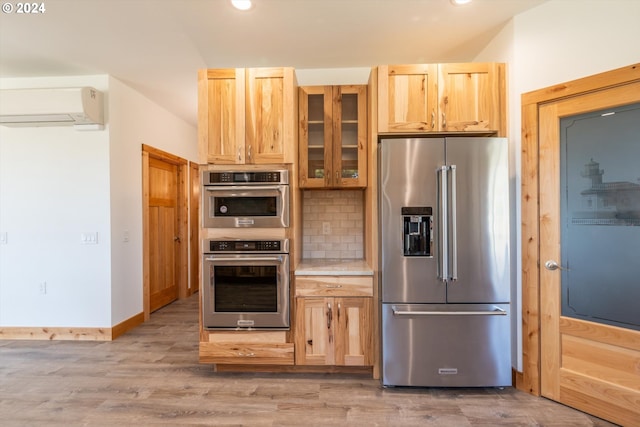 kitchen with light brown cabinets, stainless steel appliances, a wall mounted air conditioner, and light wood-type flooring